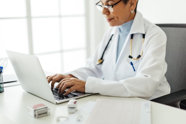Woman doctor typing on laptop